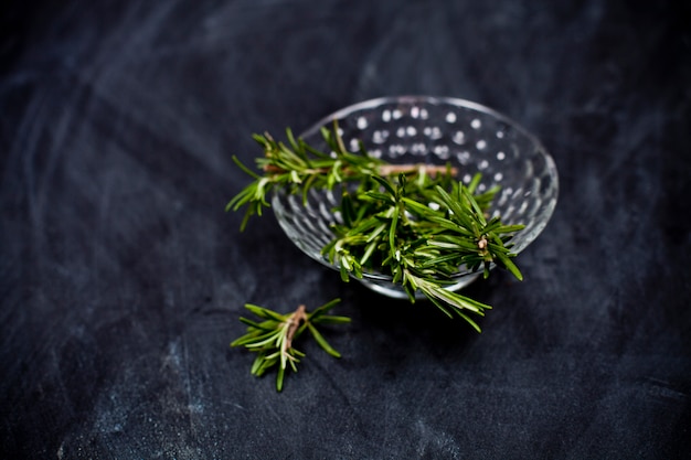 Fresh rosemary herb in glass bowl.