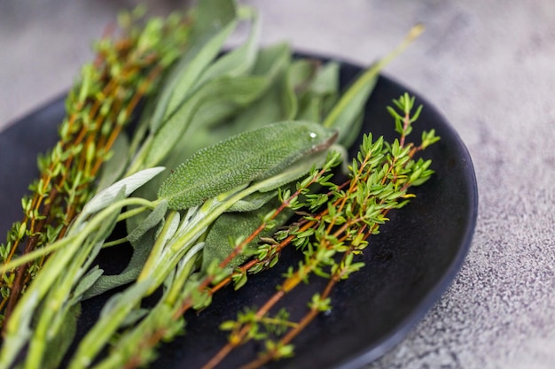 Fresh rosemary and sage spices on a black plate from the local organic garden.