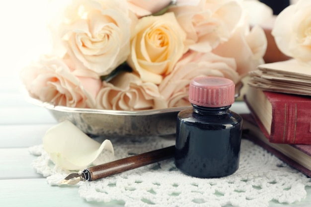 Fresh roses with old book and letters on color wooden table background. Vintage concept