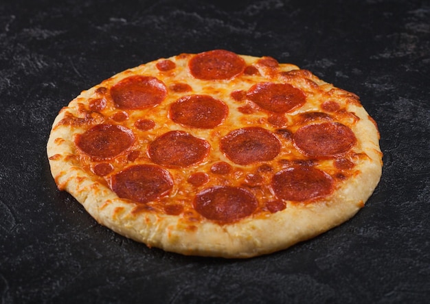 Fresh round baked Pepperoni italian pizza on black kitchen table background