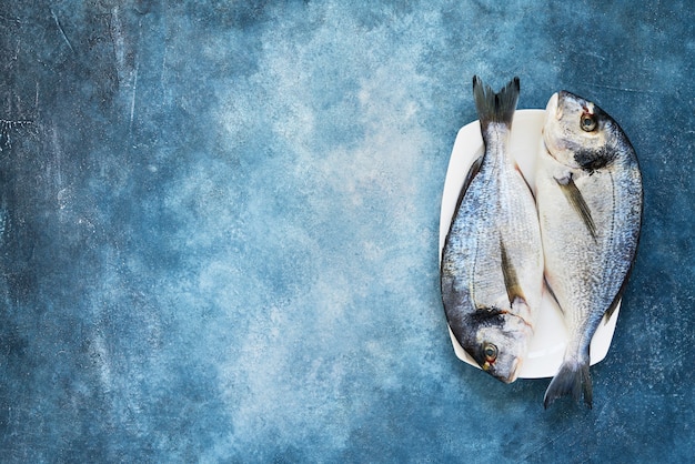 Photo fresh royal dorada on blue table. healthy food concept. top view, copy space.