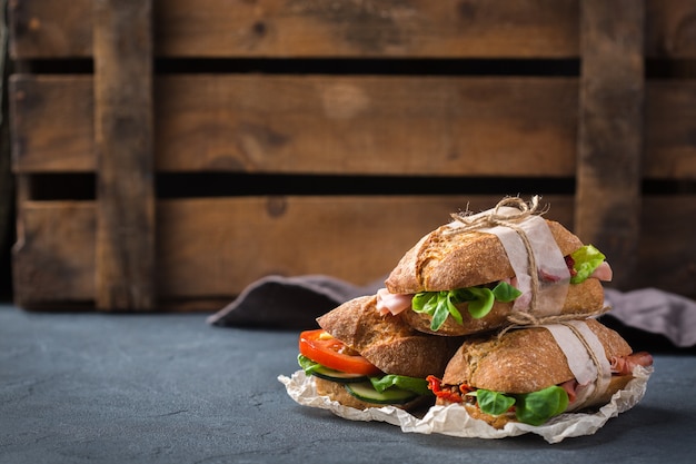 Сэндвич из свежего ржаного хлеба с ветчиной, салатом и помидорами