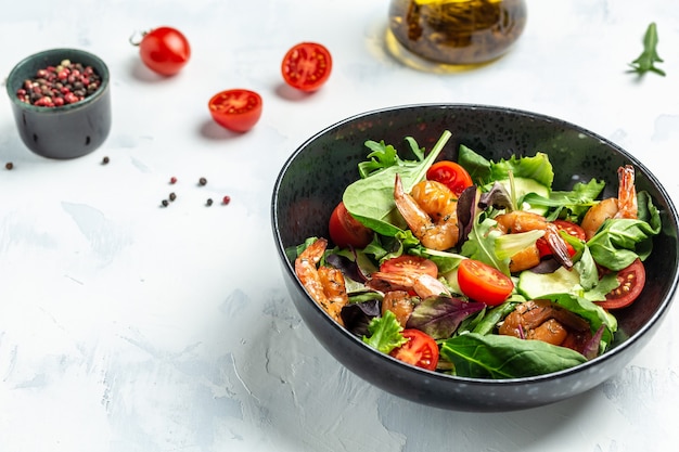 Fresh salad bowl with avocado and shrimps in bowl, Delicious breakfast or snack on a light background, top view.