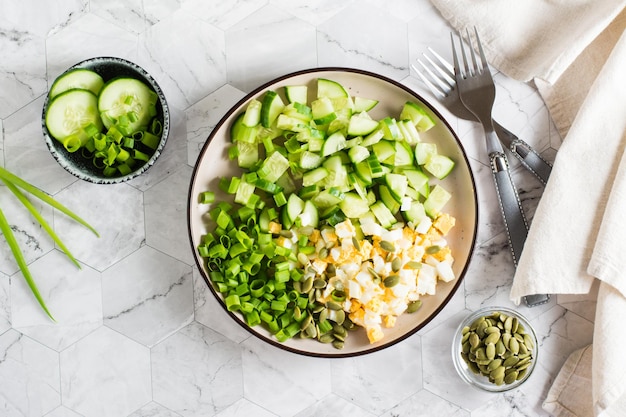 Свежий салат из огурцов, вареных яиц и зеленого лука на тарелке Кетогенная диета Вид сверху