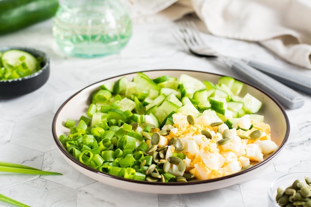 Fresh salad of cucumber boiled egg and green onion on a plate on the table Ketogenic diet