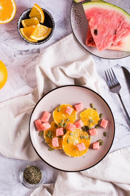 Fresh salad of orange watermelon and pumpkin seeds on a plate Organic diet Top and vertical view