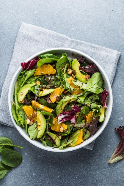 Foto insalata fresca avocado biologico e foglie di spinaci con arancia e olio d'oliva in un piatto bianco piatto vegetariano