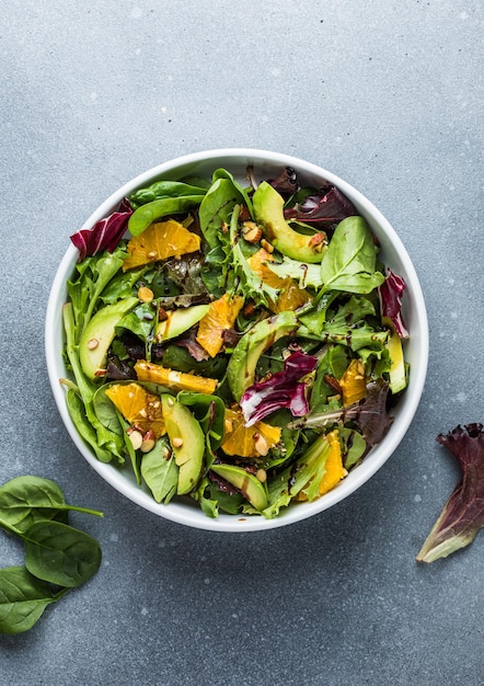 Photo fresh salad organic avocado and spinach leaves with orange and olive oil in a white plate vegetarian dish