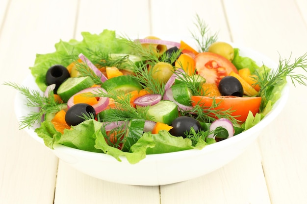 Fresh salad in plate on wooden table