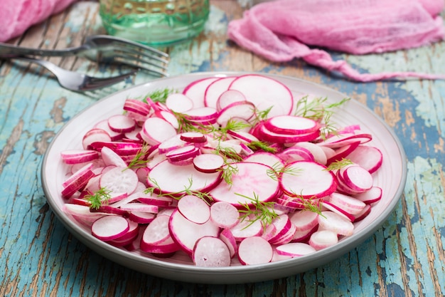 Fresh salad of radish and dill on a plate on a wooden table