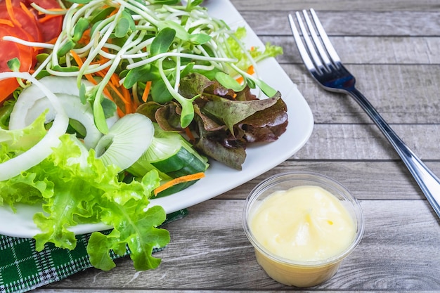 Fresh salad and salad dressing For health on a wooden table