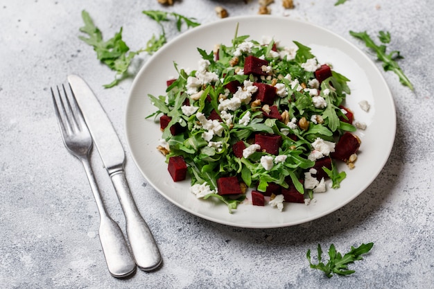 흰 접시에 arugula, 죽은 태아의 치즈, 호두, 사탕 무우와 신선한 샐러드