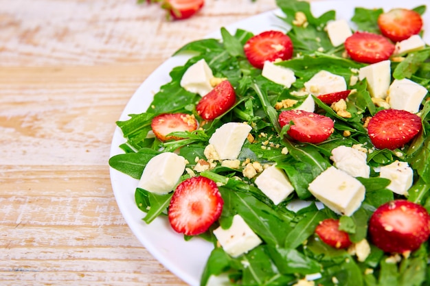 Fresh salad with arugula, strawberries, feta cheese and nuts.