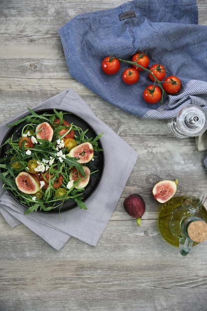 Fresh salad with arugula tomato and cheese on wooden background