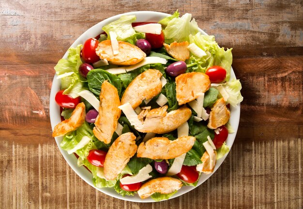 Fresh salad with chicken breast, arugula, olive and tomato