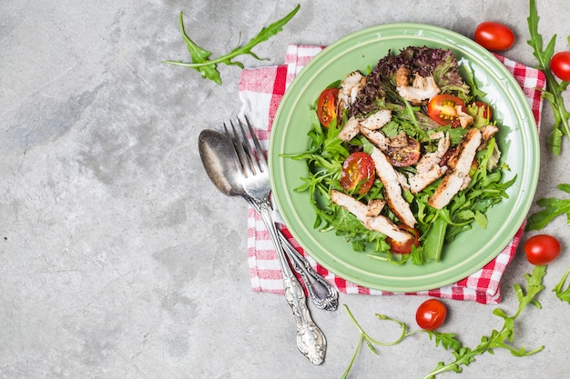 Fresh salad with chicken breast, arugula and tomato. Top view