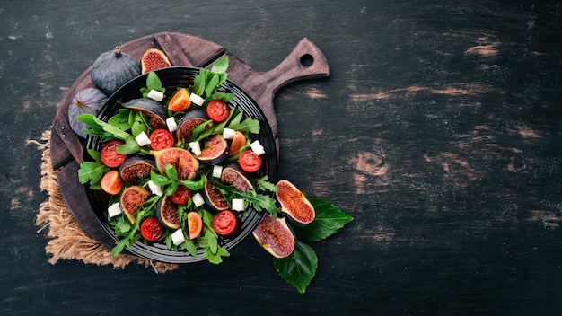 Fresh salad with figs arugula leaves cherry tomatoes and feta cheese Free space for text Top view