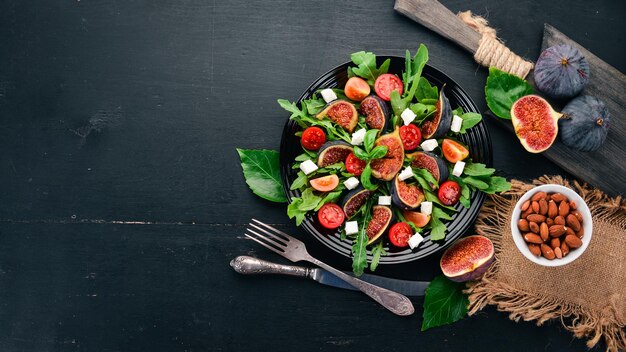 Fresh salad with figs arugula leaves cherry tomatoes and feta cheese Free space for text Top view