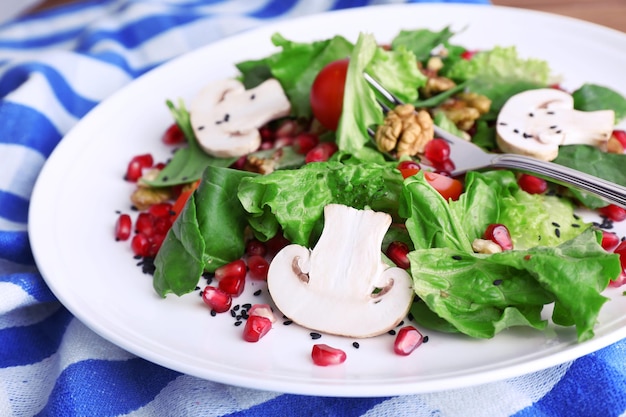 Fresh salad with greens garnet and spices on plate on table closeup