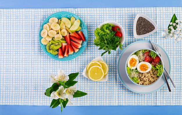 Fresh salad with oatmeal, tomatoes, lettuce, microgreens and boiled egg and fruit plate