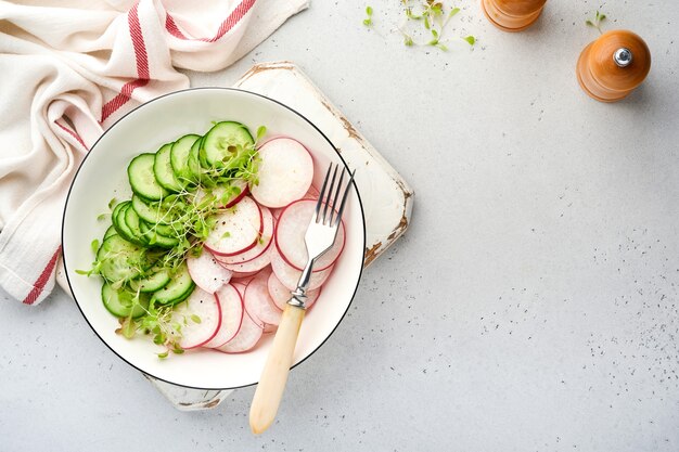 fresh salad with red radish, cucumber, vegetables, microgreen radishes in white plate