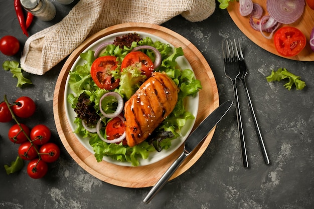 Fresh salad with roasted chicken breast on a wooden board
