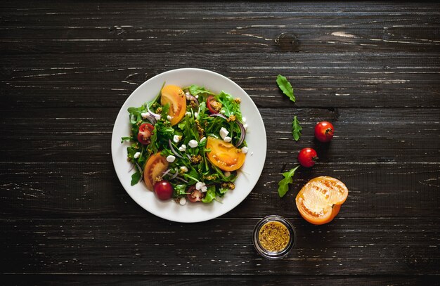 Fresh salad with tomatoes, mixed greens ,nuts, eggs, on wooden background . Healthy food.