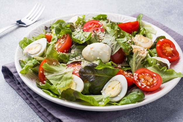 Fresh salad with tomatoes and quail eggs and lettuce.