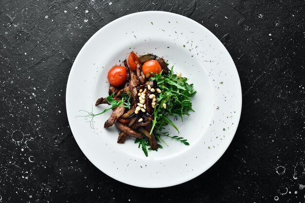 Fresh salad with veal arugula veal pine nuts and eggplant Healthy food On a white plate Rustic style