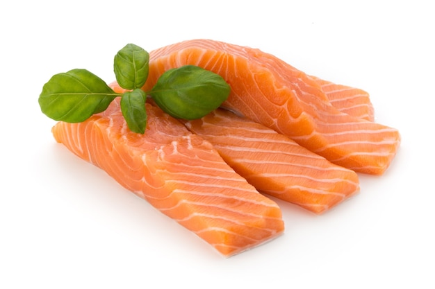 Fresh salmon fillet with basil on the white surface.