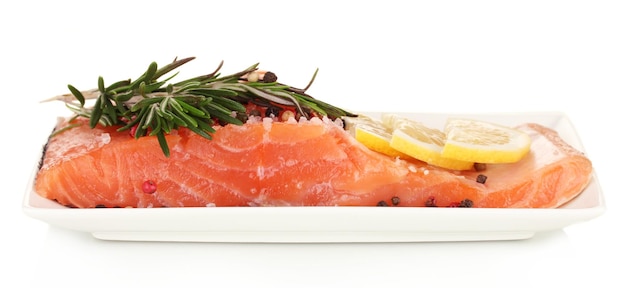 Fresh salmon fillet with herbals and lemon slices on plate isolated on white