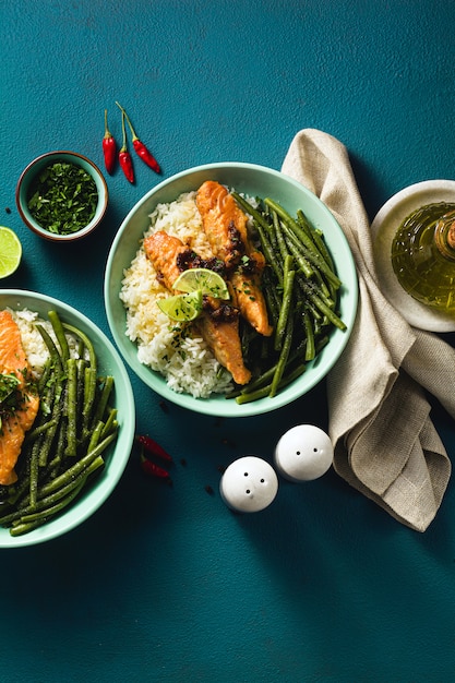 Salmone fresco fritto con zenzero e aglio nel latte di cocco, con riso basmati e fagiolini nei piatti sul tavolo. ricetta salutare per tutta la famiglia.