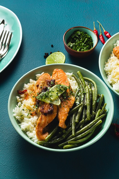 Fresh salmon fried with ginger and garlic in coconut milk, with basmati rice and green beans in plates on the table. healthy recipe for the whole family.