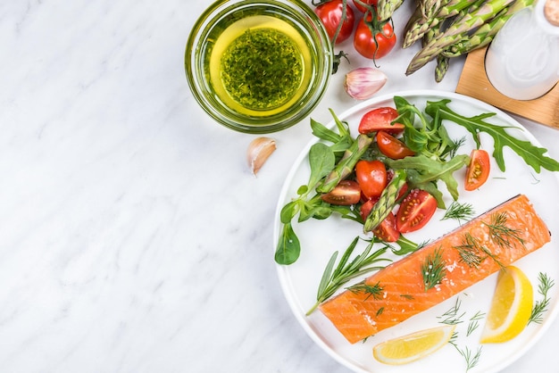 Fresh salmon pieces with saladherbs and lemon on plate