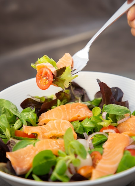 Fresh salmon salad with sweet tomatoes, pickled garlic, onions and spinach are a healthy diet 