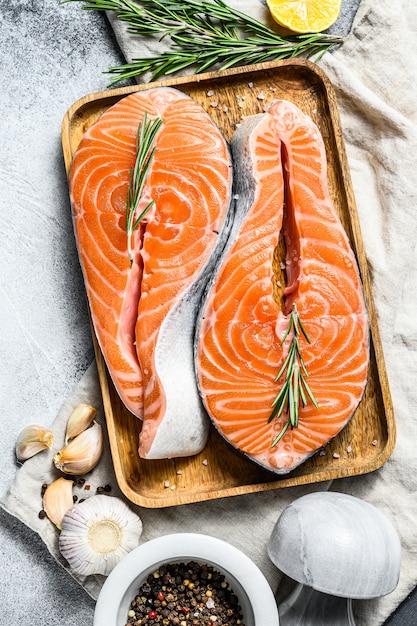 Fresh salmon steak on wooden tray with spices. Atlantic fish. Top view