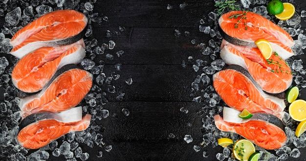 Fresh salmon steaks on ice on black background Top view Copy space