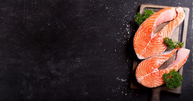 Fresh salmon steaks on a wooden board top view