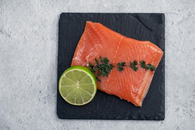 Salmone fresco con verdure e lime su sfondo concreto