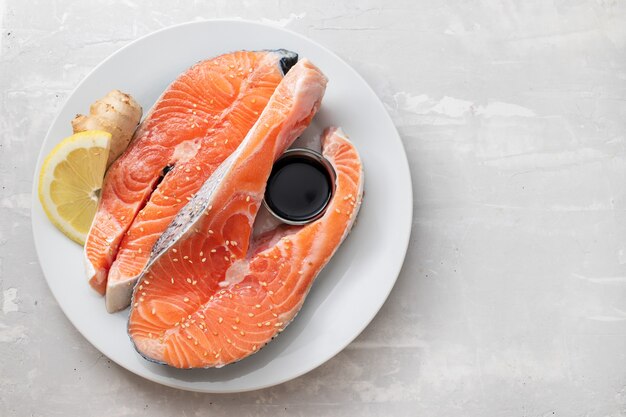 Fresh salmon with lemon, ginger and soy sauce on white plate