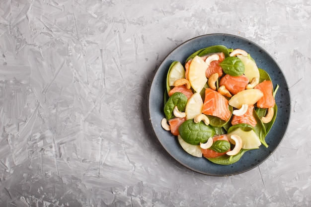 Fresh salmon with pineapple, spinach and cashew in blue plate 