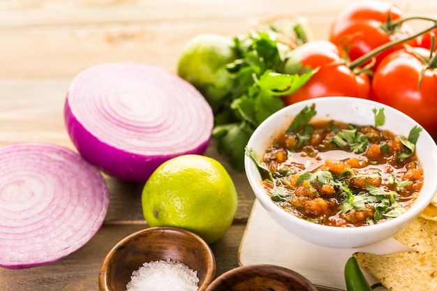 Fresh salsa in white bowl with ingredients.