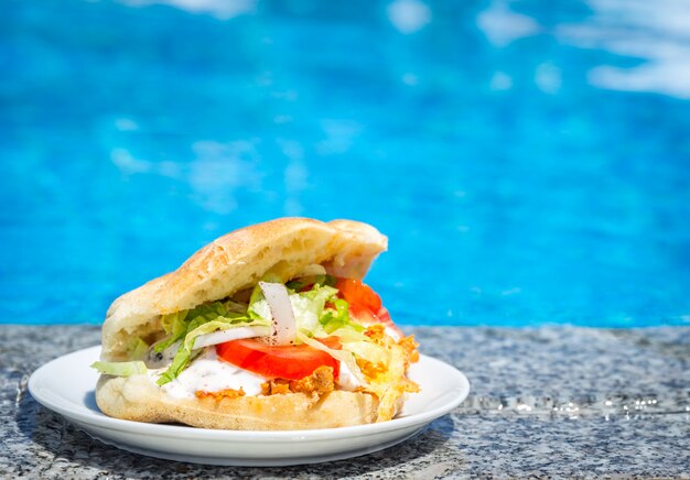 Fresh Sandwich on a plate near the swimming pool