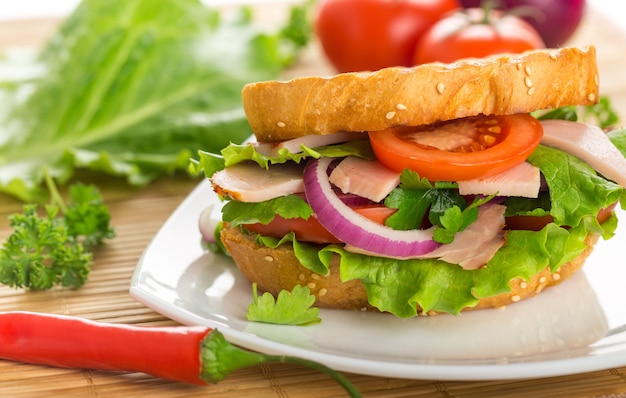 Fresh sandwich with ham and vegetables on wooden table