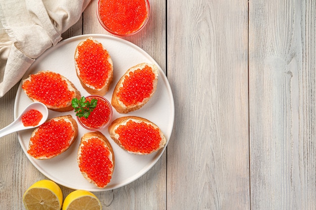 Photo fresh sandwiches with red caviar on a white plate on a light background. top view, copy space.