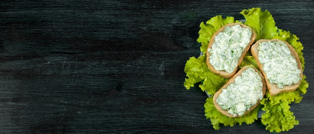 Fresh sandwiches with vegetables on a dark board on a textured surface.