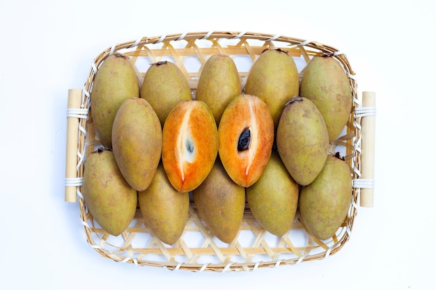 Frutta fresca di sapodilla in cesto di bambù su sfondo bianco