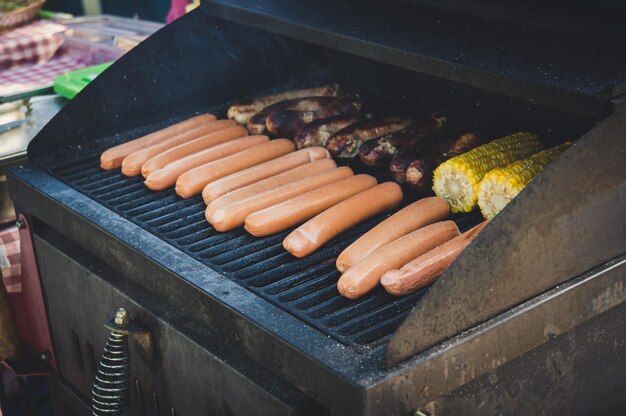 Fresh sausage and hot dogs grilling outdoors on a gas barbecue grill