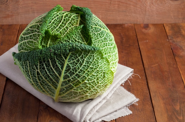 Fresh savoy cabbage closeup on a linen napkin and a rustic wooden background