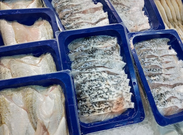 スーパーマーケットで販売する準備ができているプラスチックトレイに詰められた新鮮なシーバスの魚の切り身。